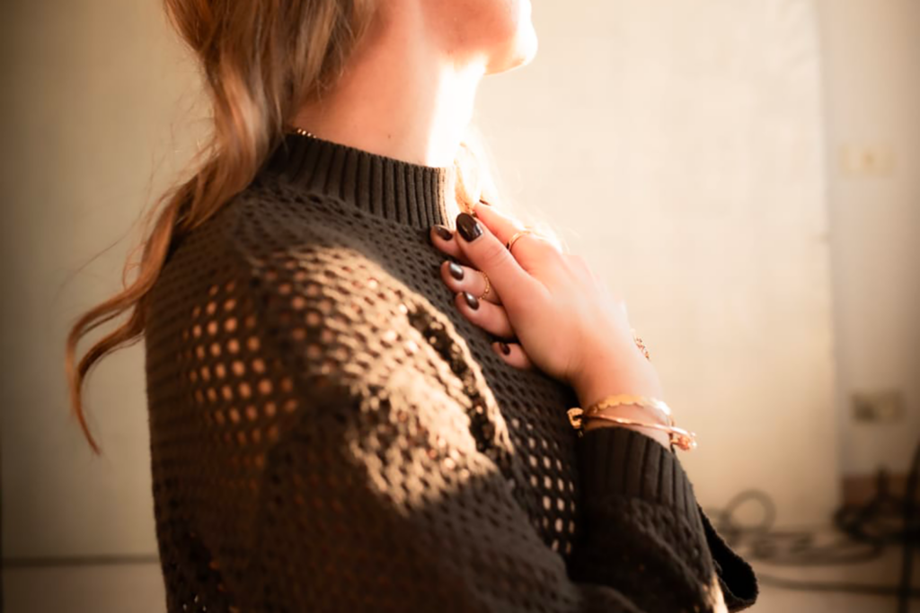 Donna bianca con i capelli lunghi biondi, il viso a tre quarti, visibile solo il mento e il collo, con le mani raccolte sul cuore.